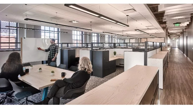 Man pointing at whiteboard with two women sitting down watching him
