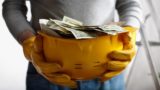Person Holding Hard Hat With Money Getty Images