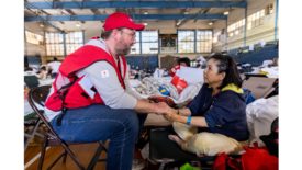 Red Cross Worker Sitting With Resident