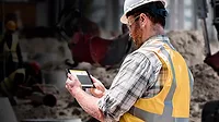 A subcontractor at a job site using an app on his tablet A subcontractor at a job site using an app on his tablet