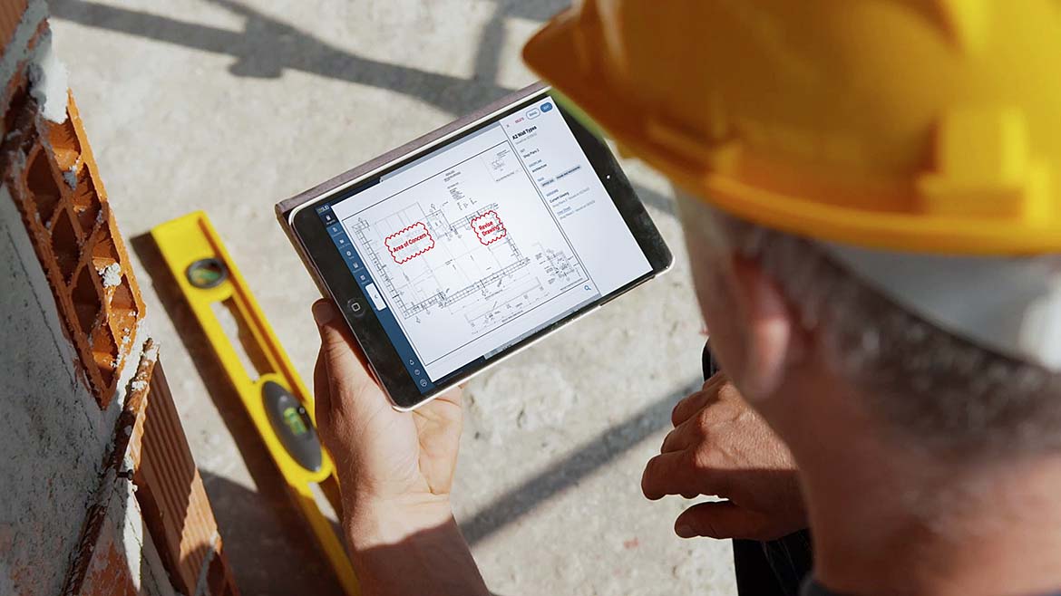 A subcontractor at a job site using an app on his tablet
