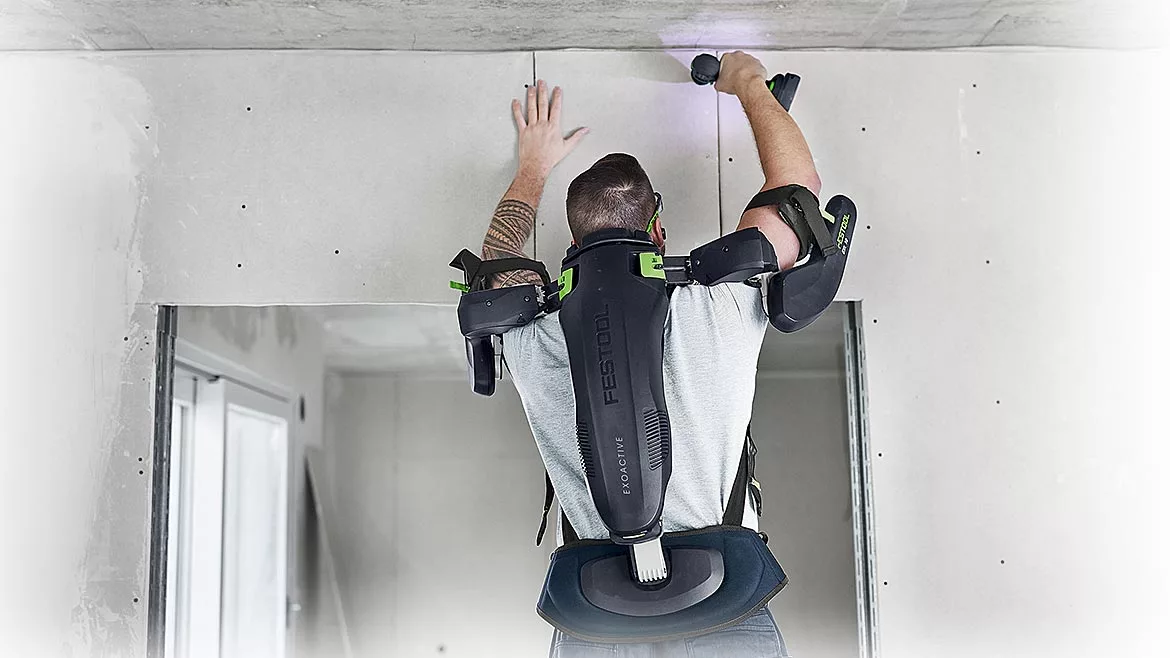 A man wearing an exoskeleton assembly while drilling