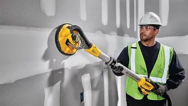 A man using DeWALT's Cordless Drywall Sander