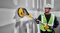 A man using DeWALT's Cordless Drywall Sander