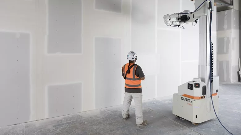 A construction worker and a drywall robot