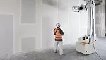 A construction worker and a drywall robot