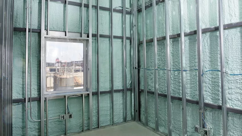 A field installer sprays Huntsman D Max Wall Insulation at a jobsite.