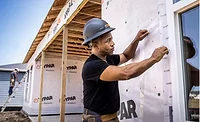 worker hangs housewrap on a building