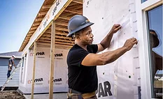 worker hangs housewrap on a building