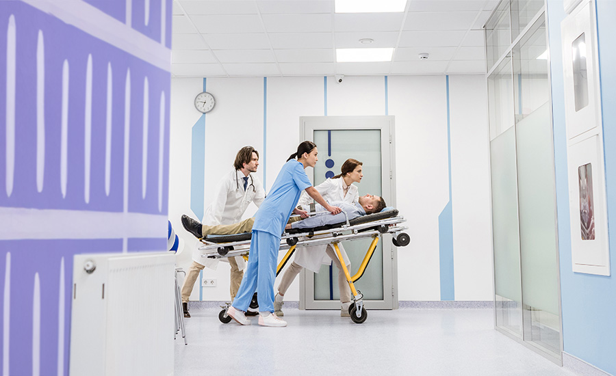 medical professionals moving a patient on a stretcher through the halls of a medical building