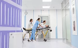 medical professionals moving a patient on a stretcher through the halls of a medical building