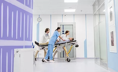 medical professionals moving a patient on a stretcher through the halls of a medical building