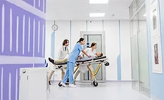 medical professionals moving a patient on a stretcher through the halls of a medical building