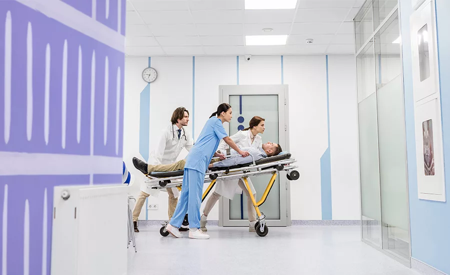 medical professionals moving a patient on a stretcher through the halls of a medical building