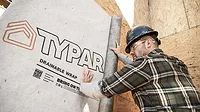 Drainable Housewraps Man installing Typar drainable wrap on a building wall.