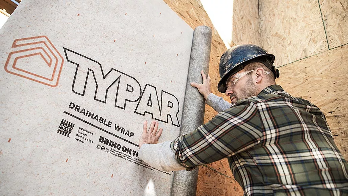  Man installing Typar drainable wrap on a building wall. 