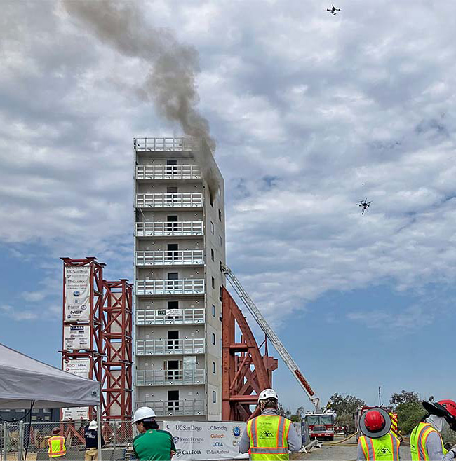 Drones circle a building during a controlled fire test
