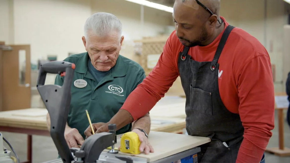 An educator teaches construction skills to a student