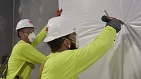 Workers on a jobsite making it safer with wrap and staples