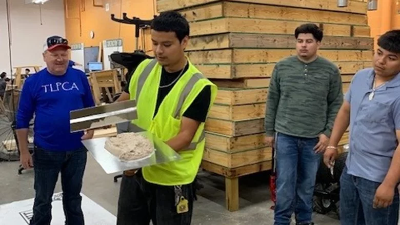 A hands on demonstration of high school students using a hawk and trowel