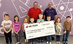 Two men stand behind eight children holding an oversized check