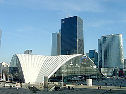 The CNIT exhibition hall in Paris, a large curved-shell structure in the La Défense business district surrounded by high-rise office towers.