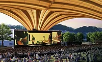 Freedom-Arch-Vancouver Rendering of Vancouver's Freedom Mobile Arch amphitheater showing a large crowd beneath the sweeping mass-timber roof with mountains visible beyond the stage.