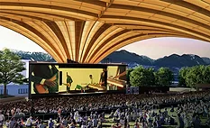 Freedom-Arch-Vancouver Rendering of Vancouver's Freedom Mobile Arch amphitheater showing a large crowd beneath the sweeping mass-timber roof with mountains visible beyond the stage.