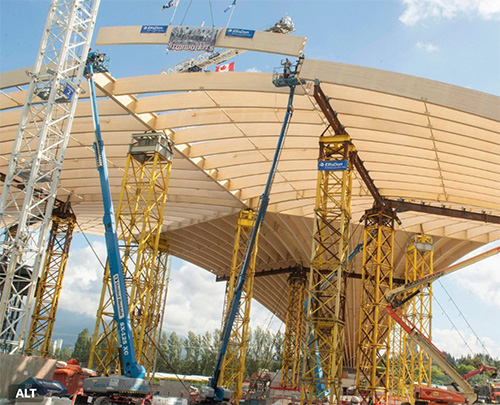 Freedom Mobile Arch under construction with cranes, temporary support towers and timber roof arches being assembled overhead.