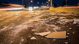Drywall strewn across a highway at night