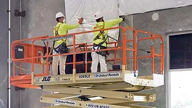 2 builders in PPE using an aerial lift