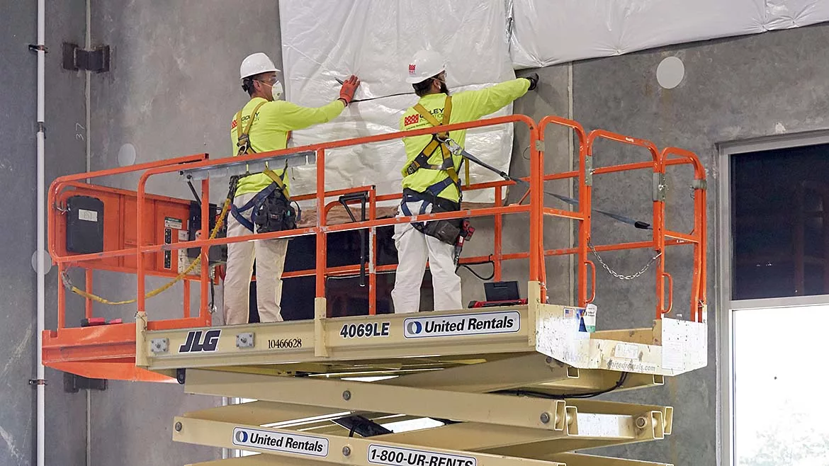 2 builders in PPE using an aerial lift