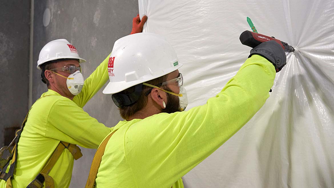 2 builders in PPE using a fastener