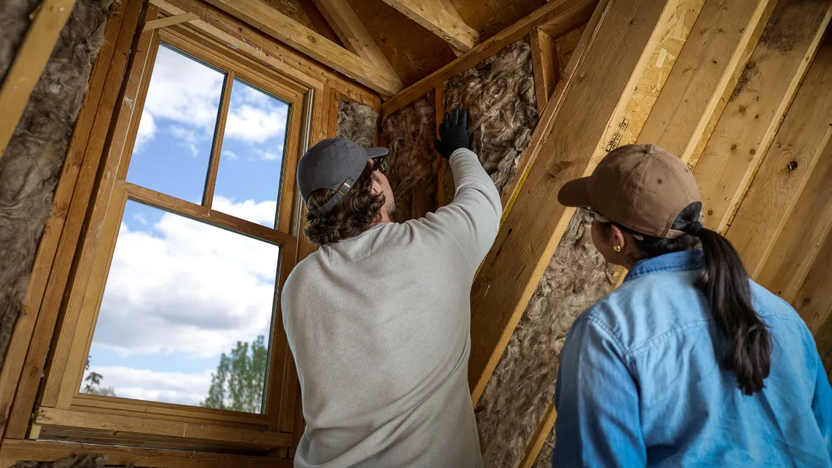 woman and man install insulation into a home attic