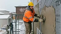 Stucco Application Tips for Extreme Weather A man applying stucco while it's cold outside